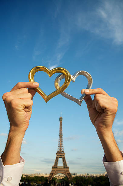 istock Hands Hold Two Shiny Hearts Up Above Eiffel Tower 182197745