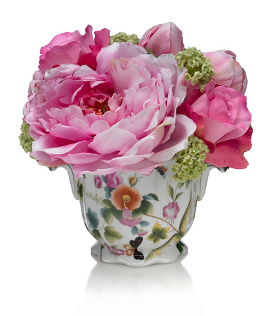 A mixed pink spring bouquet with roses and a peony in a flowered porcelain pot. Image has a path which may be used to delete the background if desired. Photographed on a bright white background. Extremely high quality faux flowers.