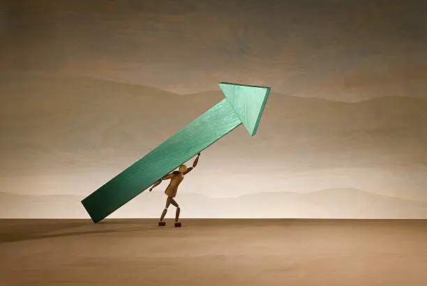 A small figure carrying a large green direction arrow.