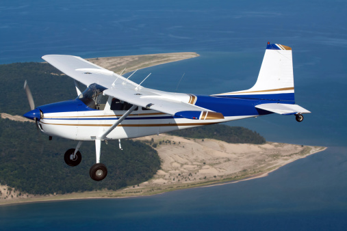 A small private airplane flying over a lake.