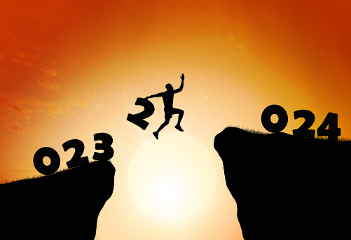silhouette man jumps to make the word Happy New Year 2024 with sunrise. New Year 2024 is coming concept.