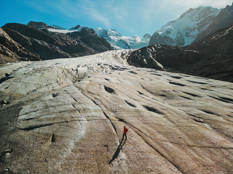 Awe-inspiring aerial view of woman walking on glacier in Swiss Alps