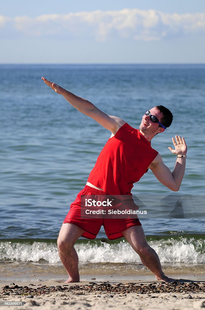 Surfer dude exercising on the beach in red swim suit. Beach Stock Photo