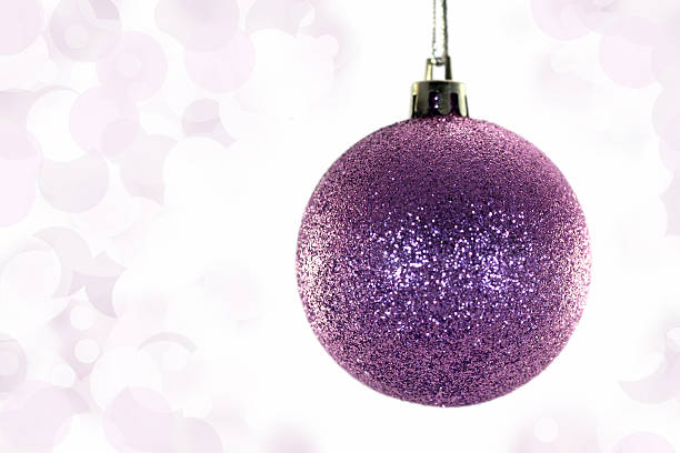 Christmas purple bauble on purple glitter blurred background with copy space. Xmas banner