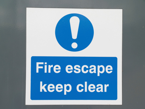Fire escape sign on textured grey door surface.