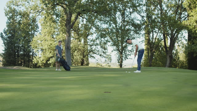A golf player is putting on green