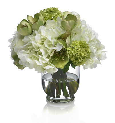 A mixed rose,hydrangea and hellebore bouquet in a glass vase. Image has a path which may be used to delete the reflection if desired. Photographed on a bright white background. Extremely high quality faux flowers.