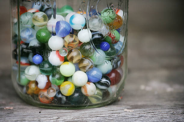 Old Colorful Marbles in a Glass Jar "Old marbles in an old glass jar.Shot with Canon 1Ds Mark II, slight color saturation and vignette added, copy space available." marble sphere stock pictures, royalty-free photos & images