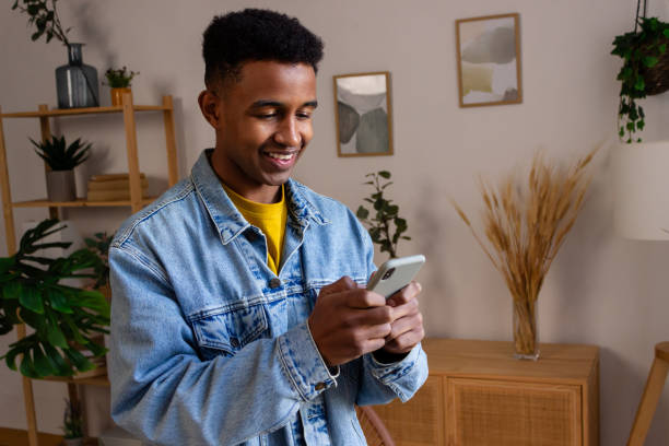 istock smiling african american man in denim jacket using smartphone at home 1822043791