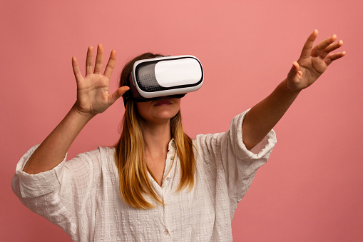 Young woman in a white shirt is using a virtual reality headset.