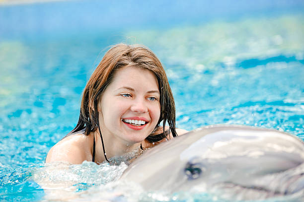 istock girl with dolphin in pool 182205807