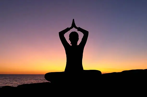 Photo of Woman Doing Yoga by the Sea at Sunset