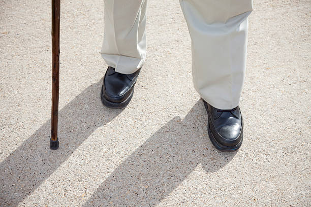 istock senior man feet and cane walking on sidewalk 182206493
