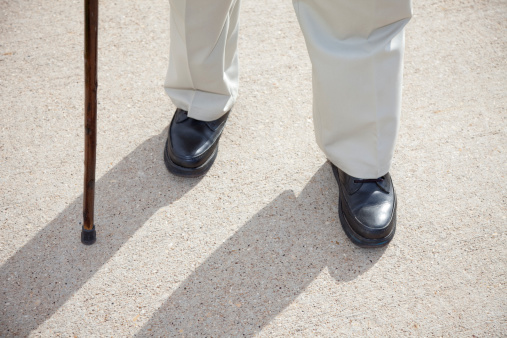 senior man feet and cane walking on sidewalk