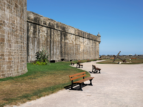 Fortified town with its the ramparts at Saint-Malo with benches and marine anchor in the background. Saint-Malo is a walled port city in Brittany in northwestern France on the English Channel. It is a sub-prefecture of the Ille-et-Vilaine department.