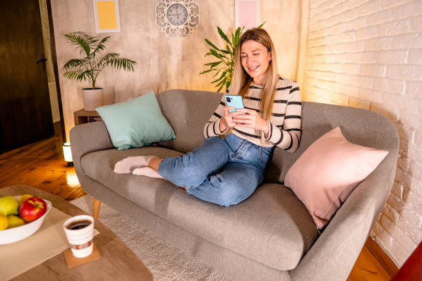 istock A young woman texting messages on her mobile phone while enjoying at home 1822080135