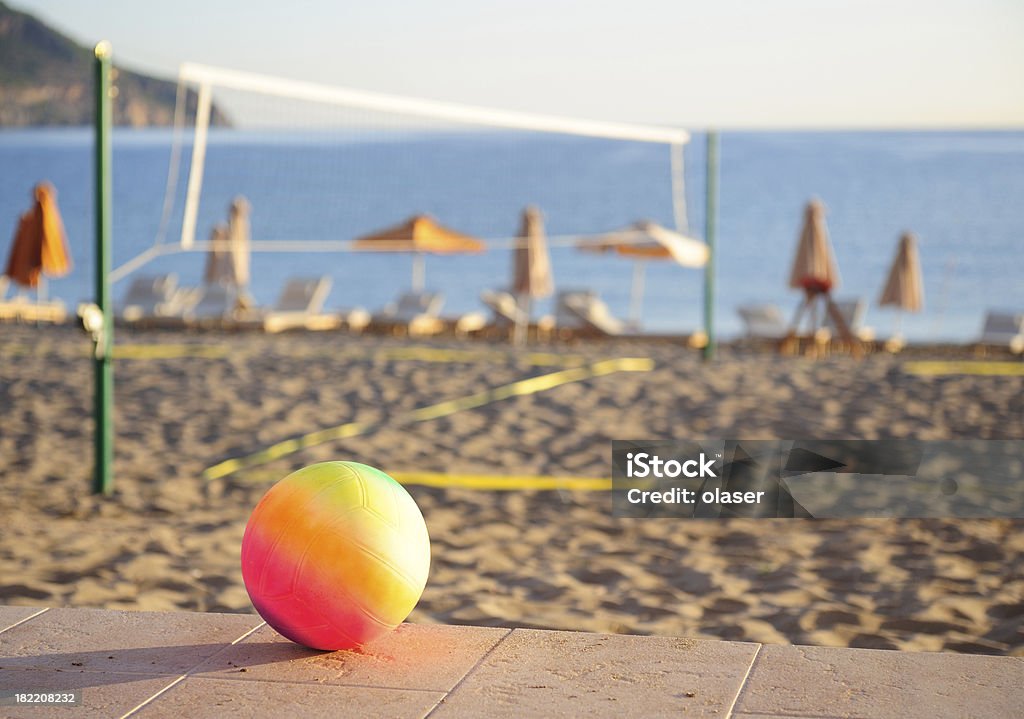 Volleyball, ready for game "A single volleyball. Beach, net and play field, resting chairs and parasol blurred in background." Agricultural Field Stock Photo