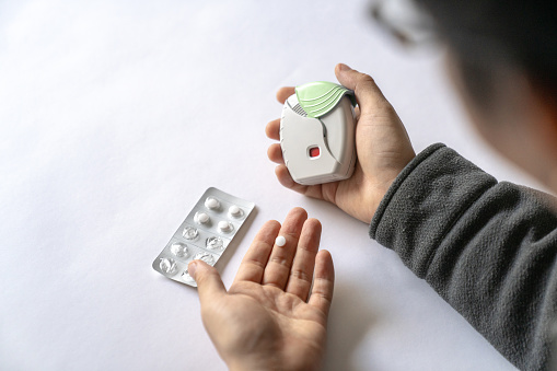 Mid adult man of Japanese ethnicity holding and dispensing asthma medication