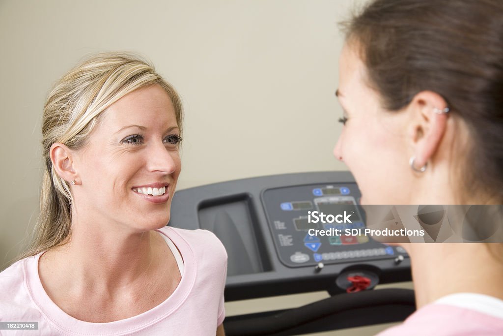 Rubia mujer hablando con un amigo en el gimnasio - Foto de stock de Actividades recreativas libre de derechos