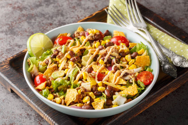 istock Ground beef taco salad with nacho chips, vegetable salsa, cheese dressed with cream sauce close-up on a plate. Horizontal 1822106321