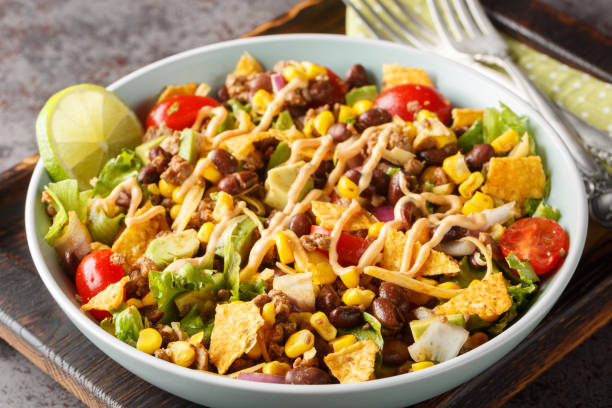 istock Beef Taco Salad made with beans, corn, nacho chips, lettuce, tomato, onion, cheese and avocado closeup on the plate. Horizontal 1822106337