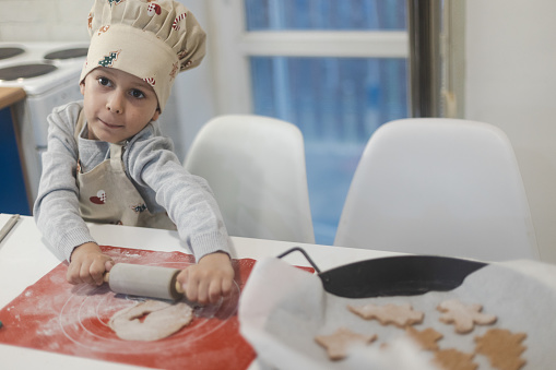 Child making Christmas gingerbread cookies. Child playing with dough