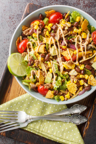 istock Homemade taco salad with nacho chips, beef, vegetable salsa, cheese dressed with spicy cream close-up on a plate on the table. Vertical top view 1822109028