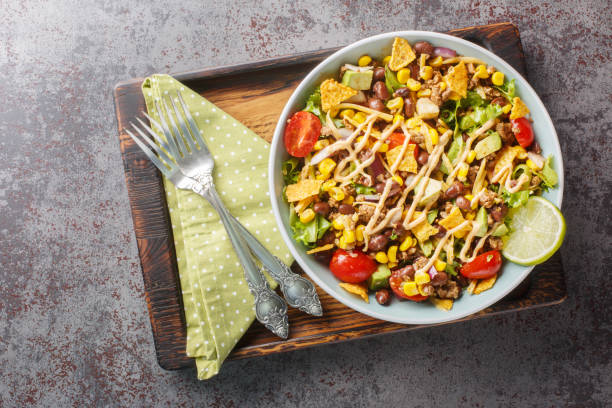 Ground beef taco salad with nacho chips, vegetable salsa, cheese dressed with cream sauce close-up on a plate. Horizontal top view
