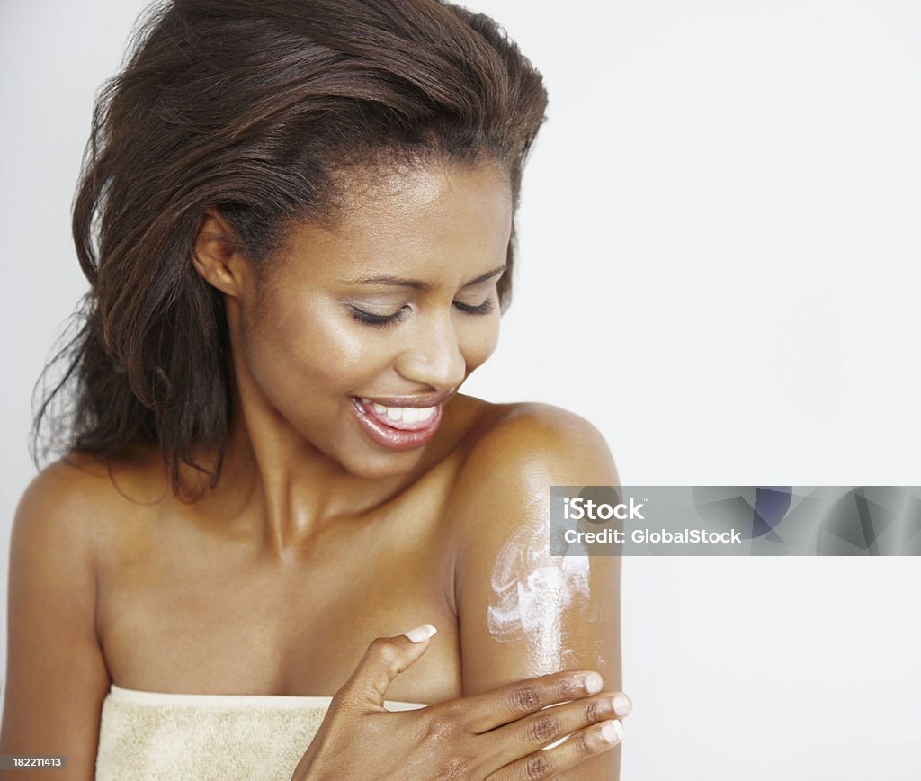 Young woman applying lotion on skin Happy young woman applying lotion on skin 20-24 Years Stock Photo