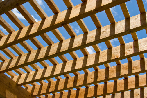 A newly constructed Pergola showing the new cedar beams with blue sky showing thru the beams