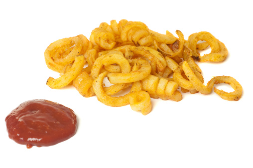 Pile of curly fries and ketchup.