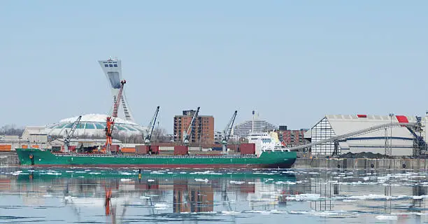 Cargo ship at dock on port of Montreal at winter time.Olympic stadium for background.