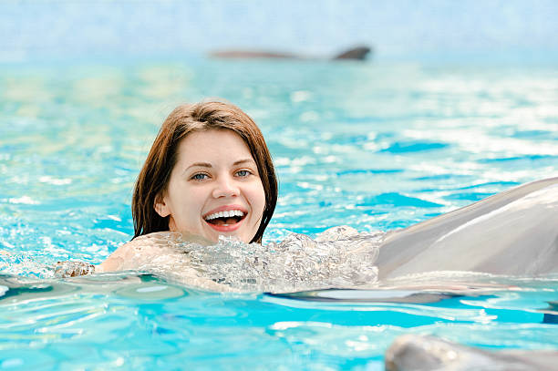 istock girl with dolphin in pool 182213582