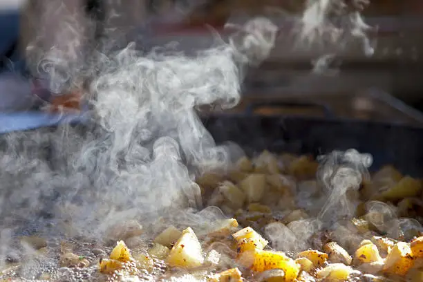 "Food street market: steam from cooking potatoes in a big pan (Real lights, not studio photo)Street market:"