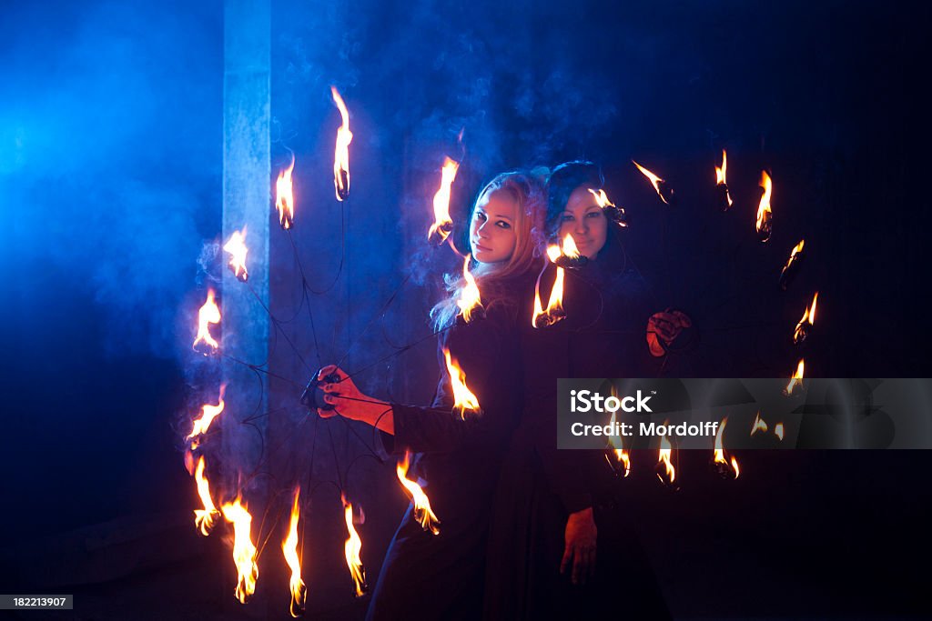 Due donna prestazioni di fuoco con fiamme in mani - Foto stock royalty-free di Adulto