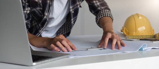 istock Young Asian engineer drawing construction project plans on plan paper on table in office 1822145562