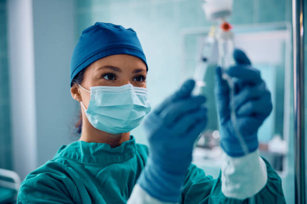 enfermera quirúrgica inyectando medicamento a través de un goteo intravenoso en el quirófano. - anestesista fotografías e imágenes de stock