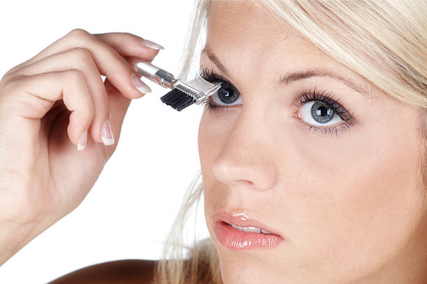 beautiful blonde woman brushing her eyelash "beautiful blonde woman brushing her eyelash, isolated on white background" lash and brow comb stock pictures, royalty-free photos & images