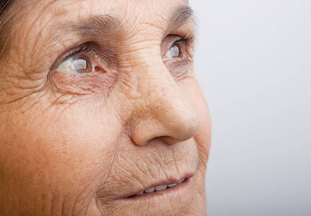 Close up cropped portrait of the blue eyes of an elderly attractive blond lady looking off to the side with a thoughtful expression in a concept of ageing gracefully