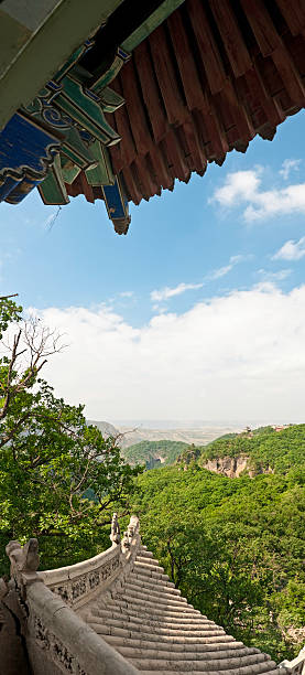 Dramatic vertical panorama across the verdant forested ridges and mountain summits of the sacred Kongtong Shan, the ancient mythical site of the meeting between Huangdi and Guangchengzi. The steep steps and rocky outcrops, pagodas and temples tower above Pingliang City, Gansu Province, China. ProPhoto RGB profile for maximum color fidelity and gamut.