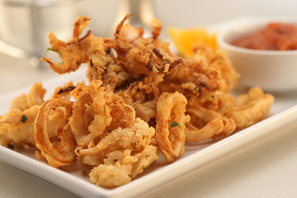 Fried Calamari "Delicious fried calamari, with both tentacles and rings, served with cocktail sauce.Vertical:" calamari stock pictures, royalty-free photos & images