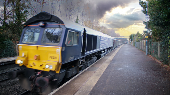 November 30th. 2023.. A diesel freightliner locomotive is pulling a goods / freight train at Hatton Station Warwickshire, England UK. It is a sunny day in Spring and there are no people in the picture.