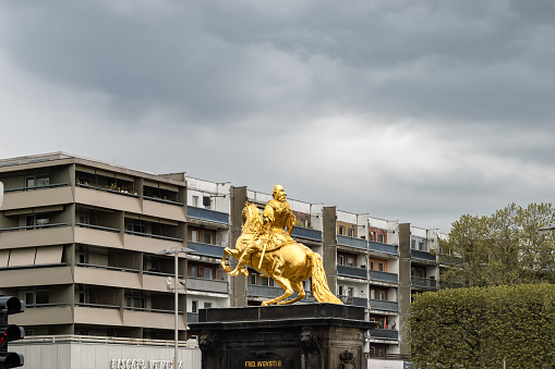 Golden Horseman from Jean Joseph Vinache and Ludwig Wiedemann, 1732–1734 at the Neustädter Markt in Dresden.\nThe statue stands in front of old run down apartment buildings. Cultural contrasts in the Neustadt in Dresden city. Residential district with broken facades.