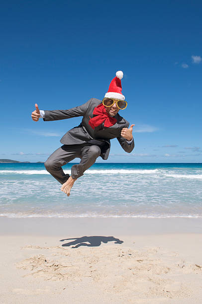 istock Thumbs Up Santa Hat Businessman Leaps on Beach 182219768