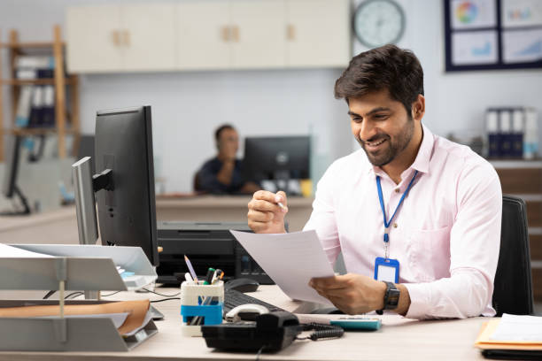 istock Businessman with Computer Reading Documents in Office stock photo 1822209311