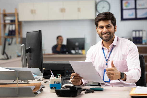Businessman with Computer Reading Documents in Office stock photo