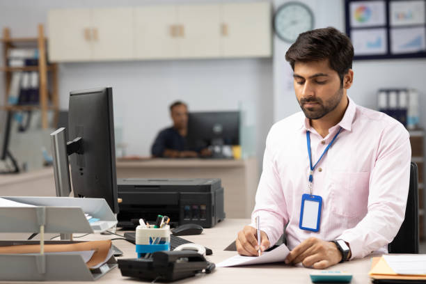 istock Businessman with Computer Reading Documents in Office stock photo 1822211511