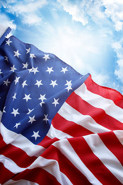 istock Rippling American flag against blue cloudy sky 182221840