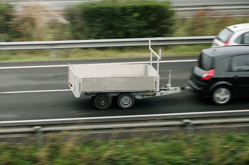 A car on a highway carrying a small cargo trailer