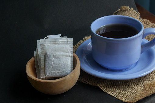 cup of tea and tea bag on black background